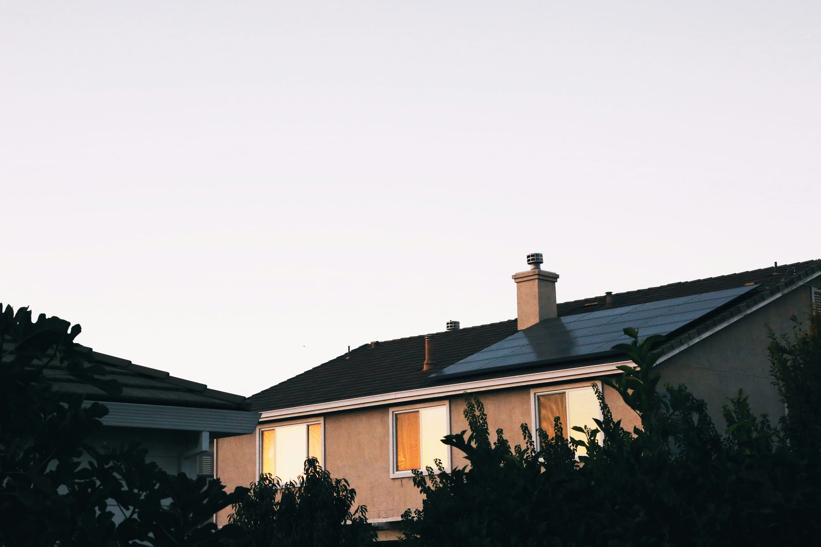 Home with rooftop solar panels glowing at dusk